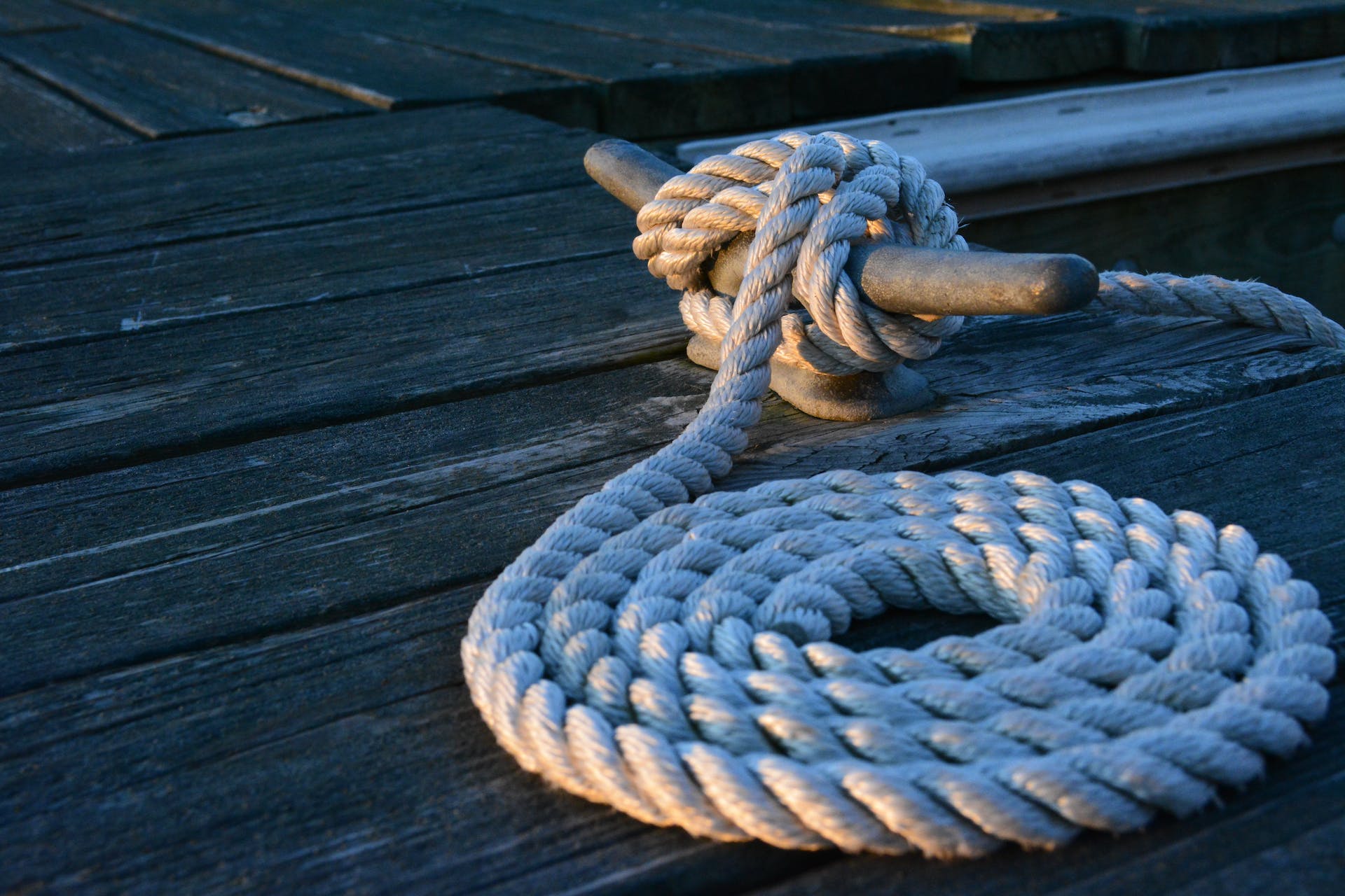 neatly coiled rope, attached to a cleat, on a wooden pier