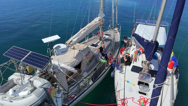Aerial view of Tinarasia rafted up alongside S/V Greta, with several crew sitting in the cockpits of both boats
